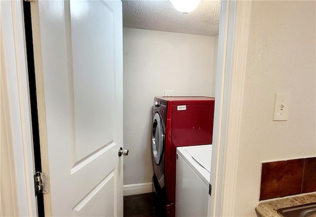 laundry area featuring laundry area, baseboards, washer and clothes dryer, and a textured ceiling