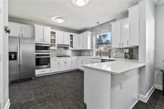 kitchen with tasteful backsplash, under cabinet range hood, appliances with stainless steel finishes, and a peninsula