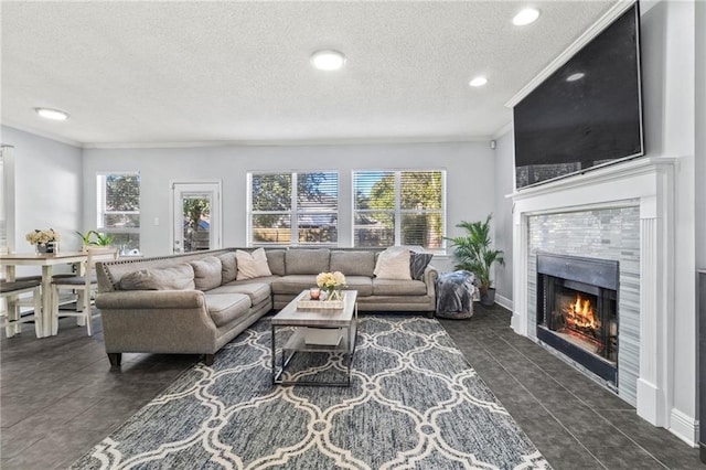 living room featuring a tile fireplace, plenty of natural light, dark tile patterned floors, and a textured ceiling