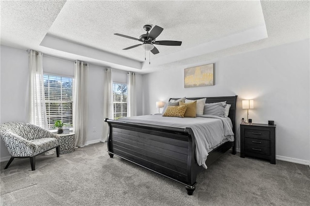 bedroom with ceiling fan, carpet floors, and a tray ceiling