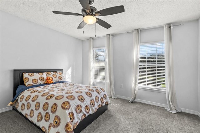 carpeted bedroom featuring baseboards, a textured ceiling, and a ceiling fan