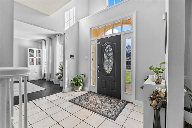 entryway with baseboards, a high ceiling, a textured ceiling, and light tile patterned floors