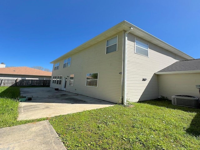 rear view of house featuring a lawn, fence, cooling unit, and a patio area
