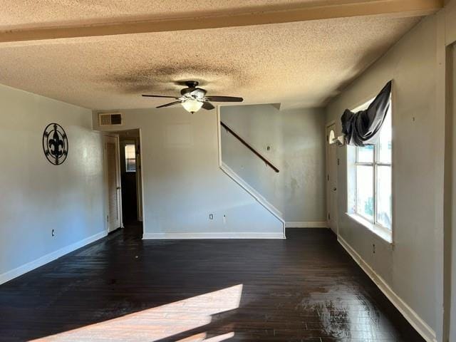 unfurnished room featuring a textured ceiling, ceiling fan, beam ceiling, and dark hardwood / wood-style floors