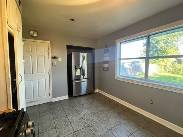 interior space featuring dark tile patterned flooring and stainless steel fridge