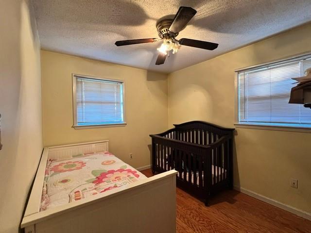 bedroom with ceiling fan, dark hardwood / wood-style floors, and a textured ceiling