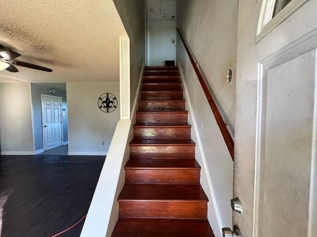 stairs featuring hardwood / wood-style flooring, ceiling fan, and a textured ceiling