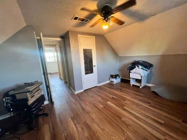 additional living space with a textured ceiling, ceiling fan, vaulted ceiling, and hardwood / wood-style flooring