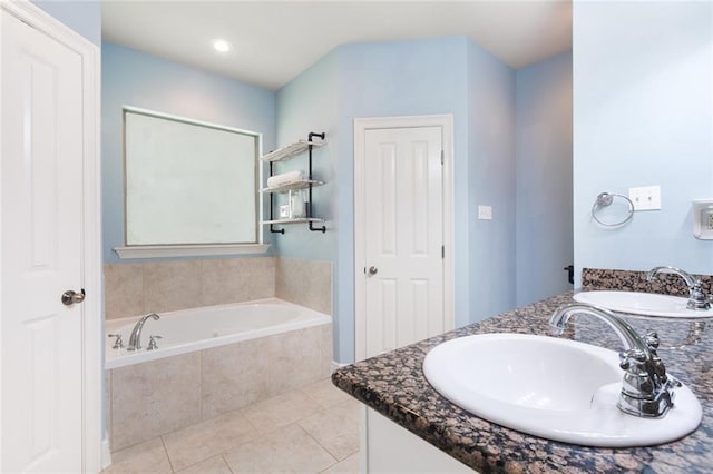 bathroom with tile patterned flooring, vanity, and tiled bath