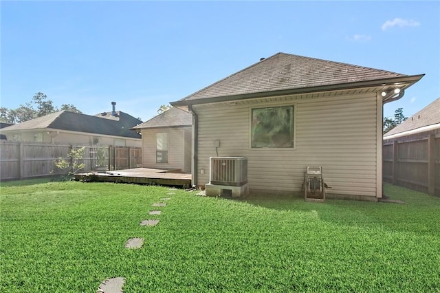 rear view of property featuring a lawn, central AC unit, and a wooden deck