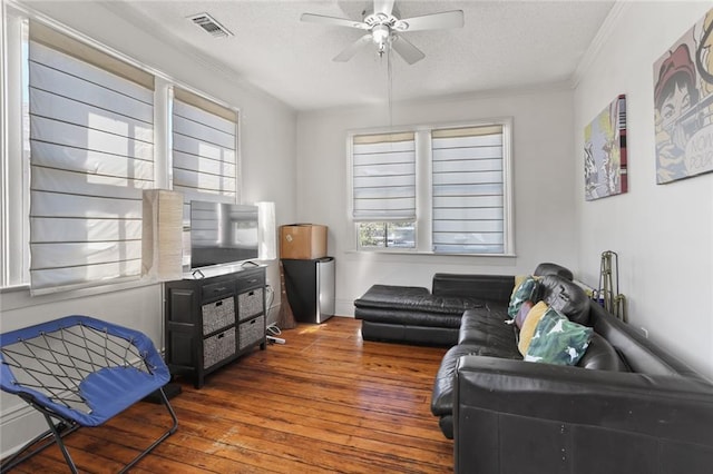 living room with a textured ceiling, dark hardwood / wood-style floors, ceiling fan, and crown molding