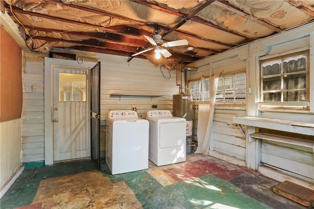 clothes washing area featuring separate washer and dryer, water heater, ceiling fan, and wood walls