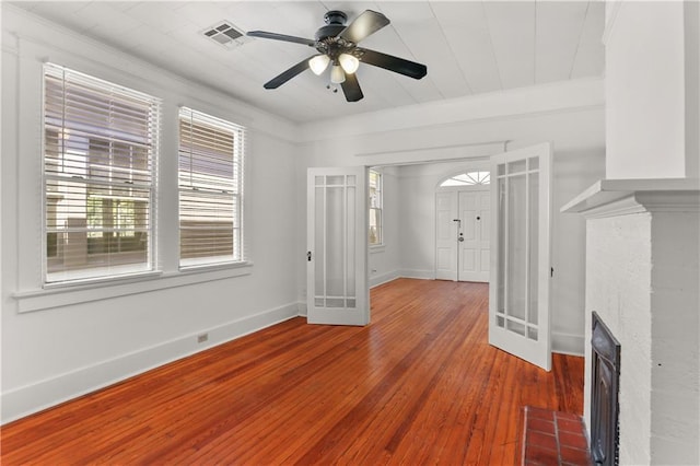 interior space with a brick fireplace, ceiling fan, wood-type flooring, and french doors