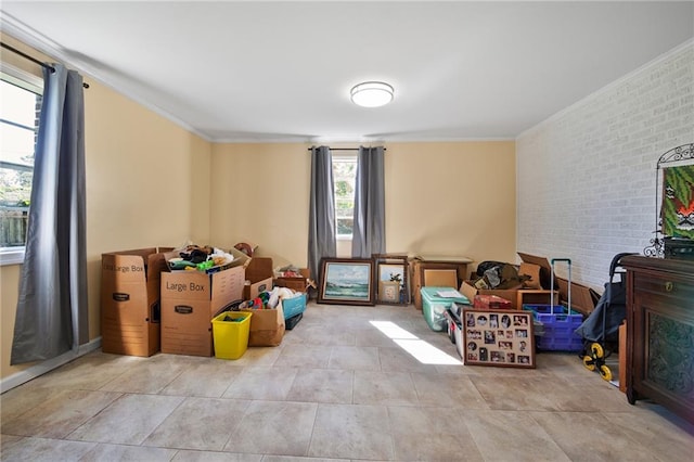 interior space with a healthy amount of sunlight, brick wall, and ornamental molding