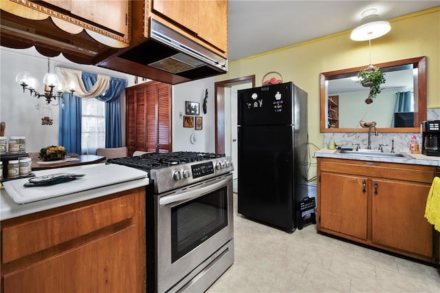 kitchen with black fridge, stainless steel gas range oven, sink, pendant lighting, and a notable chandelier