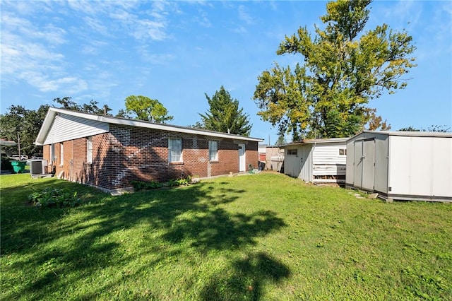 back of house with central air condition unit, a storage unit, and a lawn