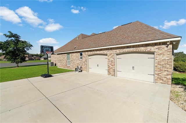 view of side of home with a garage, cooling unit, and a lawn