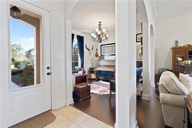 foyer with light tile patterned floors, ornamental molding, and an inviting chandelier