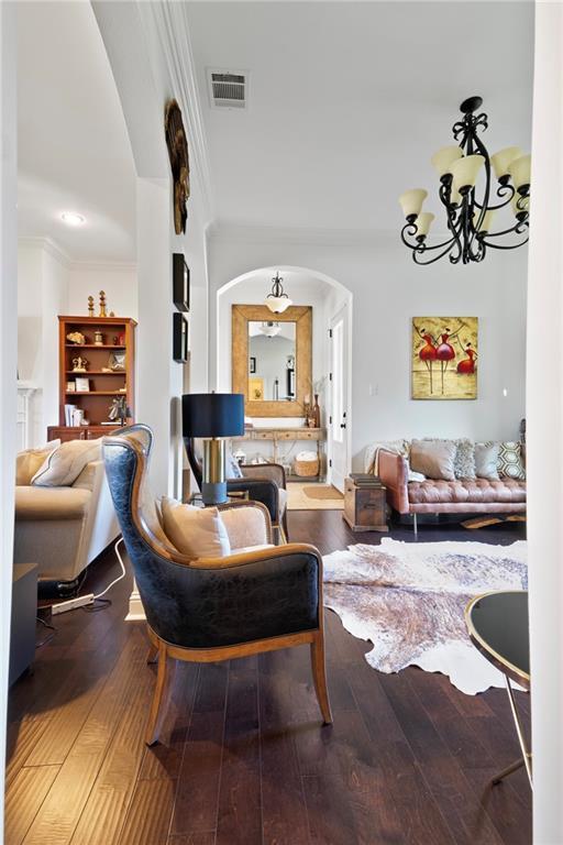 living room with wood-type flooring, crown molding, and a notable chandelier