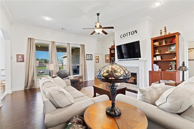 living room with dark hardwood / wood-style floors, ceiling fan, crown molding, and a high end fireplace