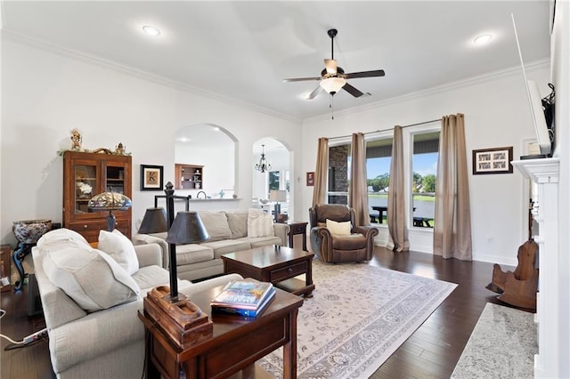 living room featuring dark hardwood / wood-style floors, ceiling fan, crown molding, and a fireplace