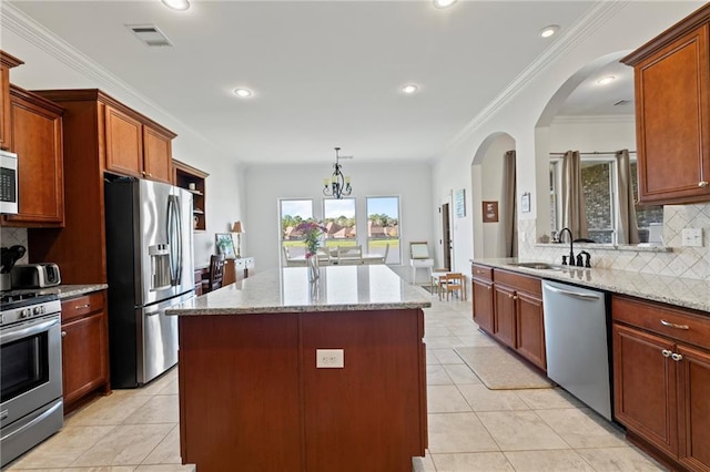 kitchen featuring a center island with sink, a notable chandelier, light stone countertops, and stainless steel appliances