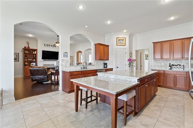 kitchen featuring light stone countertops, a breakfast bar, crown molding, sink, and a kitchen island