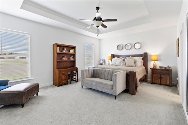 carpeted bedroom with multiple windows, a raised ceiling, and ceiling fan