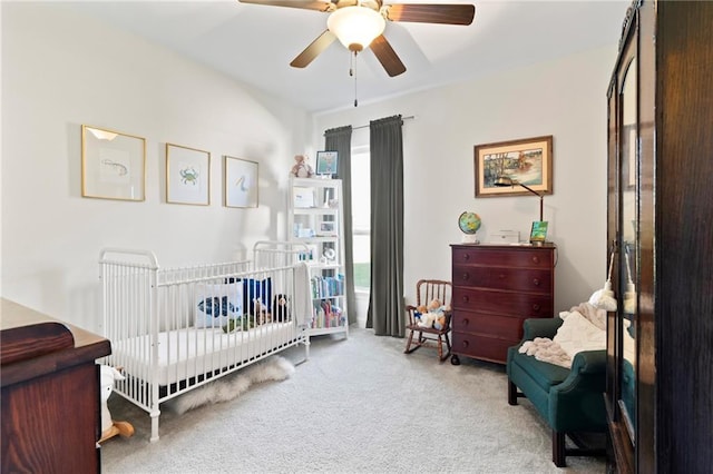 carpeted bedroom featuring a crib and ceiling fan