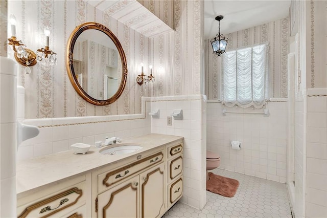 bathroom featuring tile patterned flooring, vanity, toilet, and tile walls