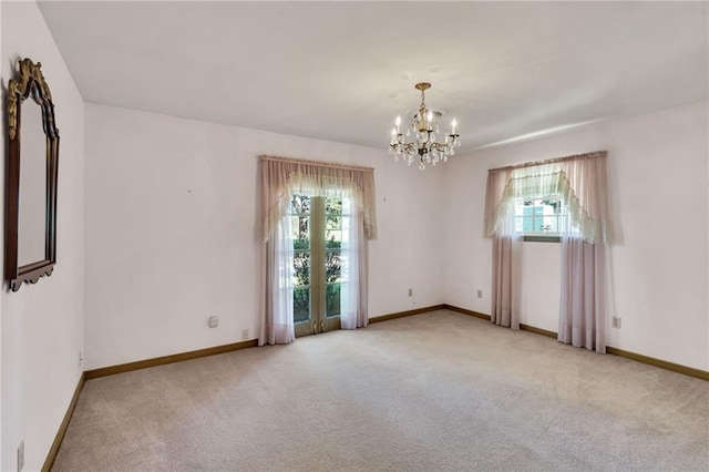 empty room featuring light carpet, a chandelier, and plenty of natural light