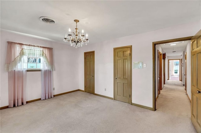 carpeted empty room with a notable chandelier and plenty of natural light