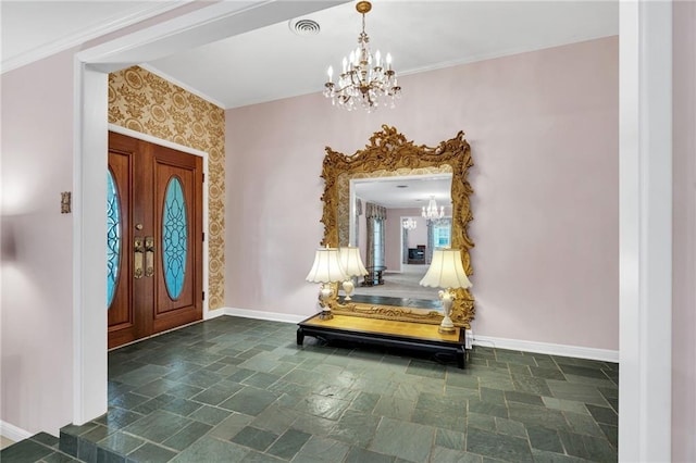 foyer entrance with ornamental molding, french doors, and a notable chandelier