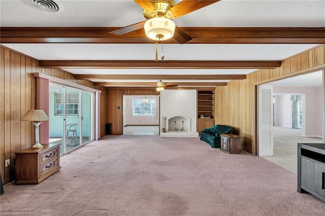 carpeted living room with wood walls, ceiling fan, beam ceiling, and a textured ceiling