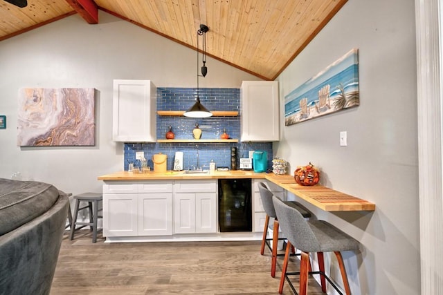 bar with pendant lighting, wood counters, white cabinets, and decorative backsplash