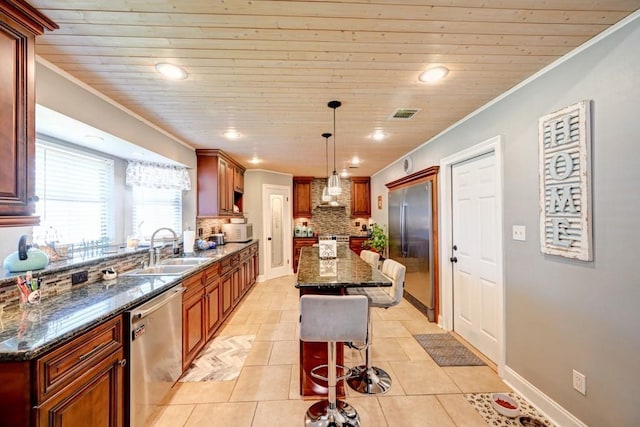 kitchen featuring decorative backsplash, dark stone counters, stainless steel appliances, pendant lighting, and a center island