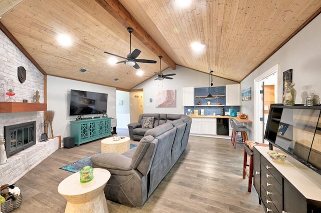 living room with lofted ceiling with beams, hardwood / wood-style flooring, a brick fireplace, and wooden ceiling