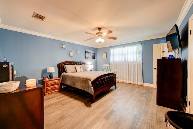 bedroom with light wood finished floors, baseboards, visible vents, and crown molding