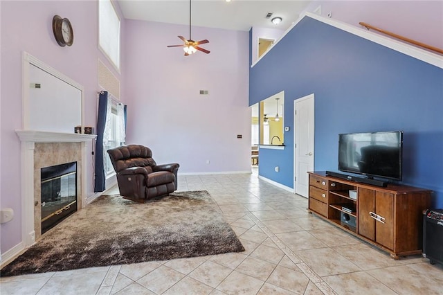 living room featuring plenty of natural light, ceiling fan, high vaulted ceiling, and a tiled fireplace