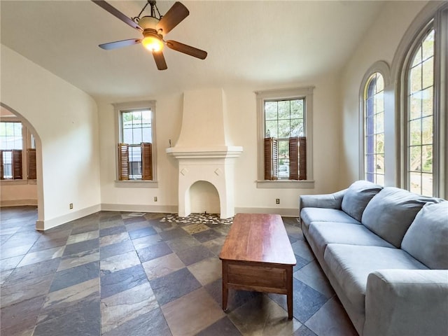 living room with ceiling fan and a large fireplace