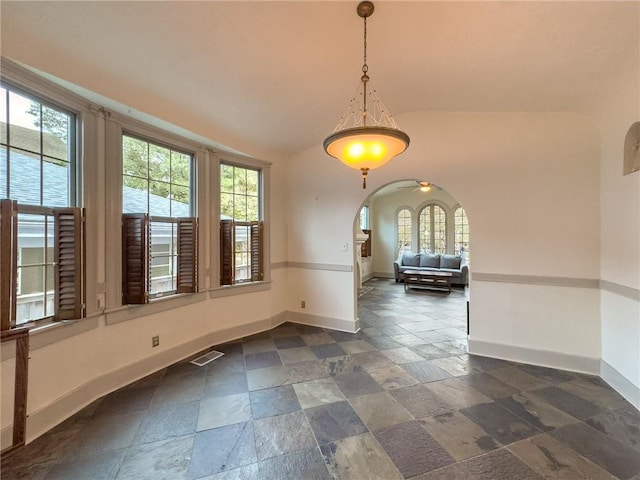 unfurnished dining area with ceiling fan, a healthy amount of sunlight, and vaulted ceiling