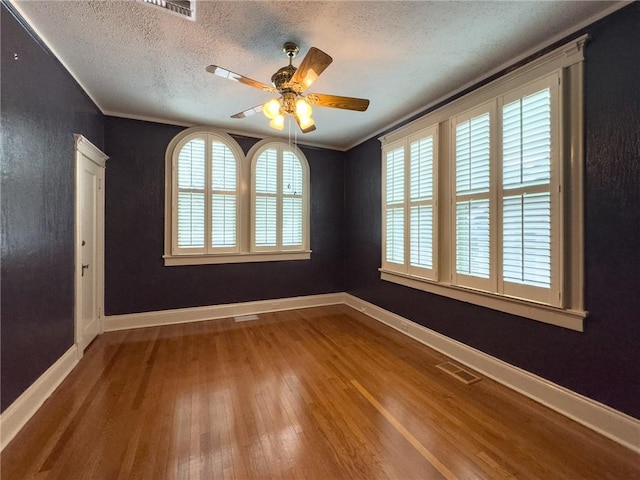 empty room with wood-type flooring, a textured ceiling, ceiling fan, and crown molding