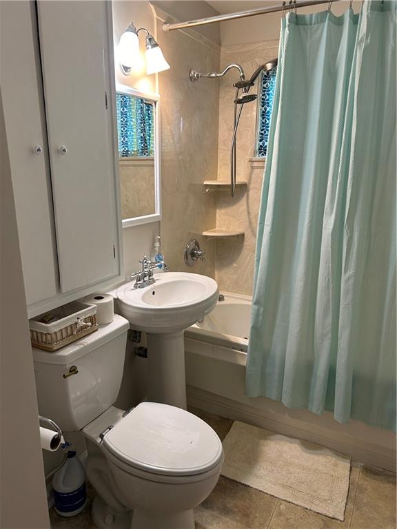 bathroom featuring tile patterned flooring, toilet, and shower / bath combo with shower curtain