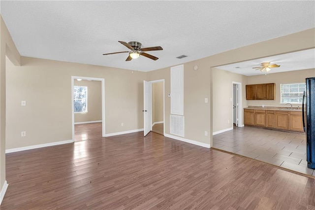 unfurnished living room featuring a textured ceiling, a wealth of natural light, sink, and dark hardwood / wood-style floors