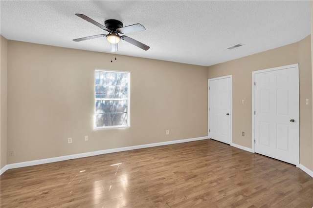 unfurnished room with ceiling fan, wood-type flooring, and a textured ceiling