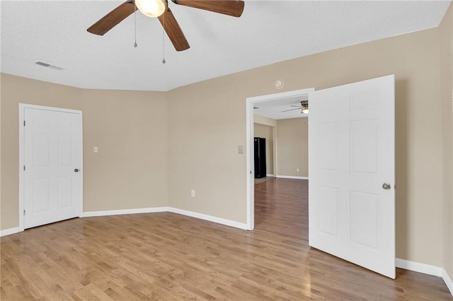 spare room featuring a textured ceiling, light hardwood / wood-style floors, and ceiling fan