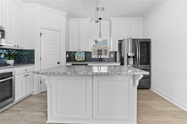 kitchen with a center island, stainless steel appliances, light stone counters, pendant lighting, and decorative backsplash