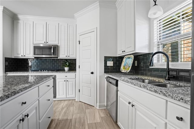 kitchen featuring hanging light fixtures, white cabinetry, sink, and stainless steel appliances