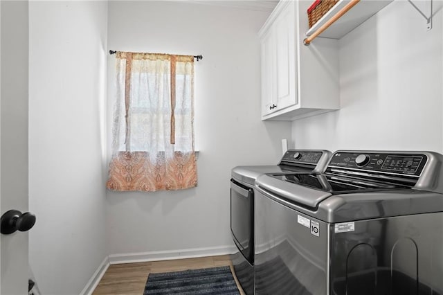 clothes washing area featuring cabinets, independent washer and dryer, and hardwood / wood-style flooring