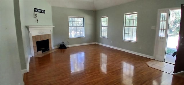 unfurnished living room with a fireplace, hardwood / wood-style flooring, and a healthy amount of sunlight